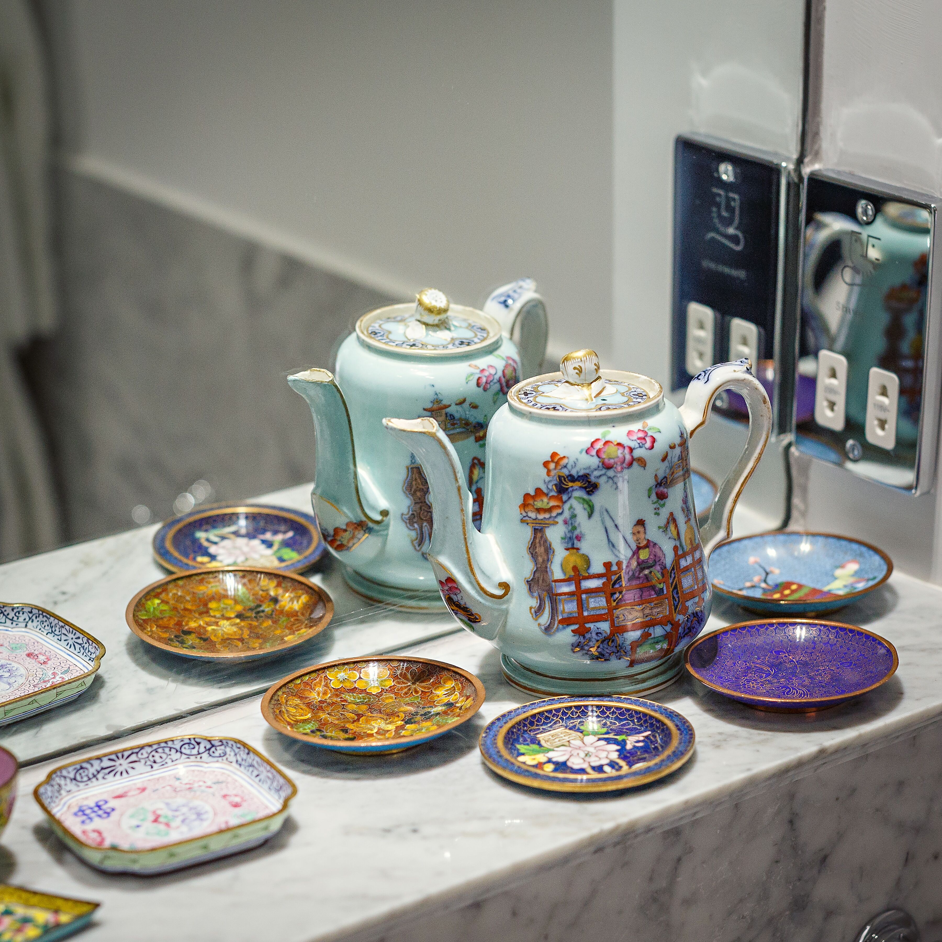 A collection of ceramic tea sets and bowls on a marble countertop.