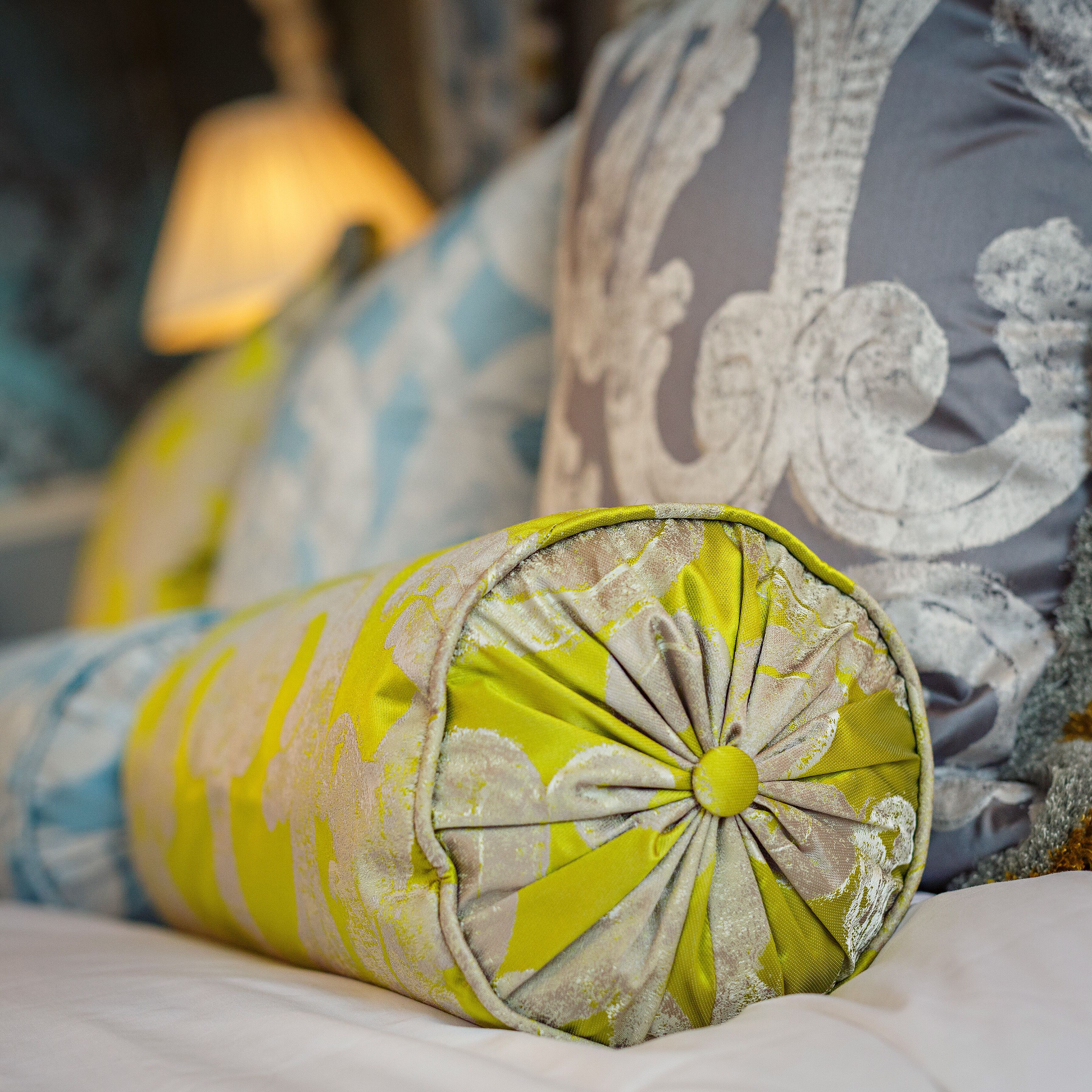 A close-up of a decorative pillow with a floral pattern and a button detail.