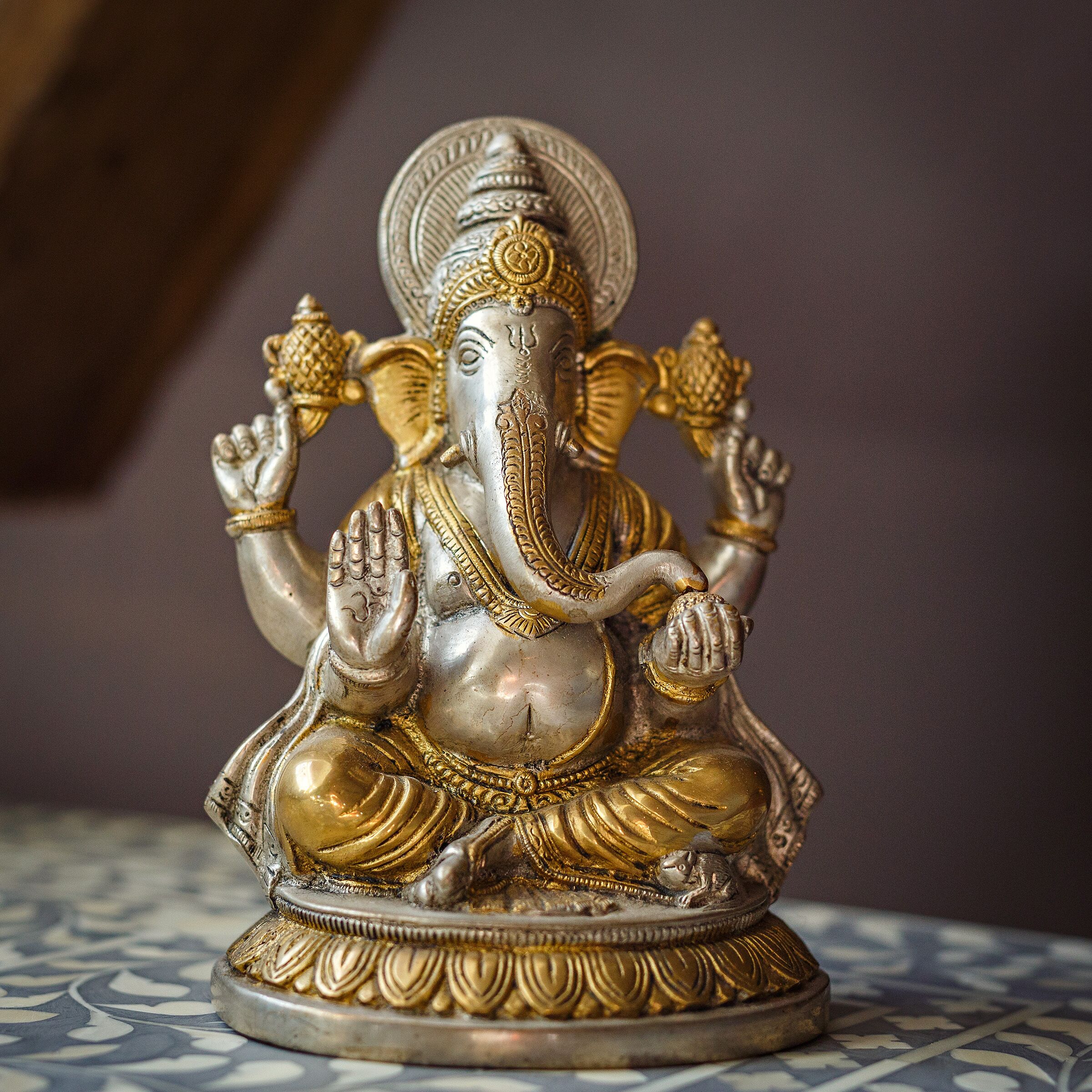 A statue of a deity with multiple arms, seated on a base with a patterned design.