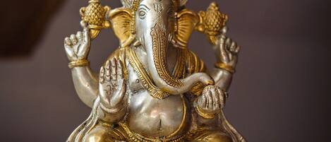 A statue of a deity with multiple arms, seated on a base with a patterned design.