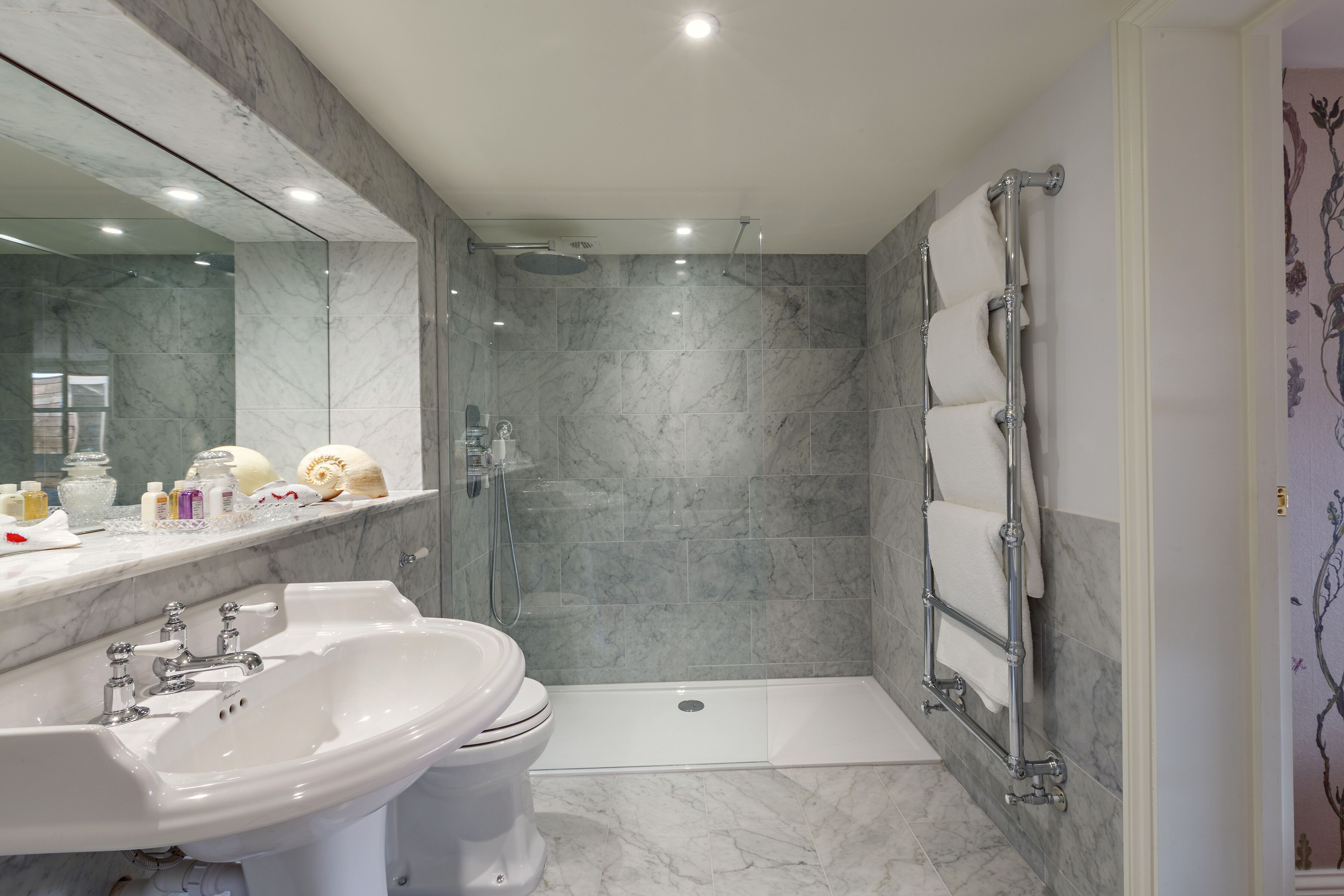 Un baño moderno con lavamanos de mármol, inodoro y ducha a ras de suelo.