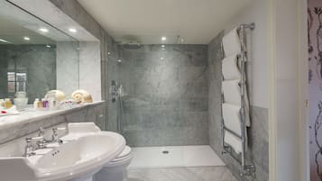 Un baño moderno con lavamanos de mármol, inodoro y ducha a ras de suelo.