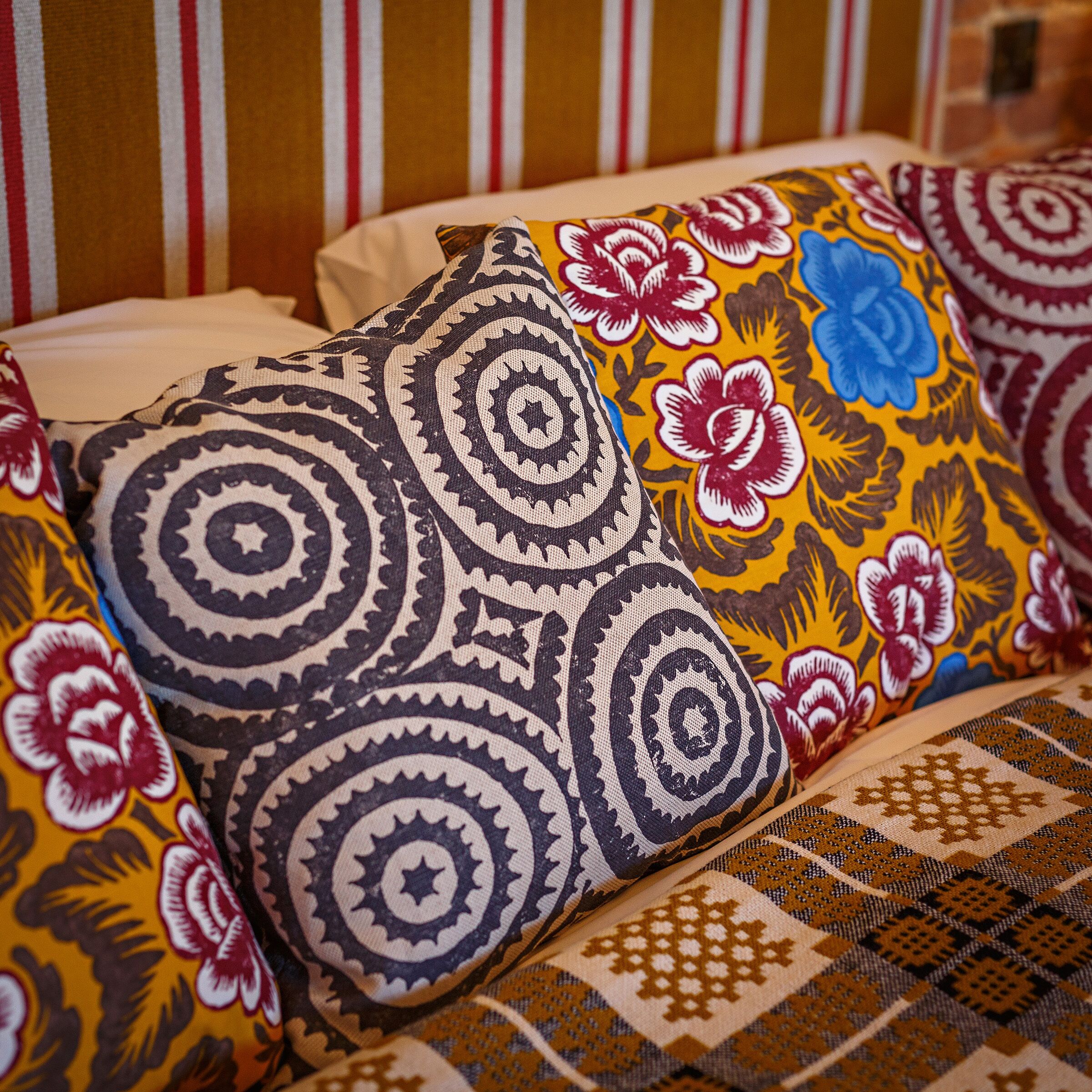 Una cama con almohadas estampadas y un cabecero a rayas.
