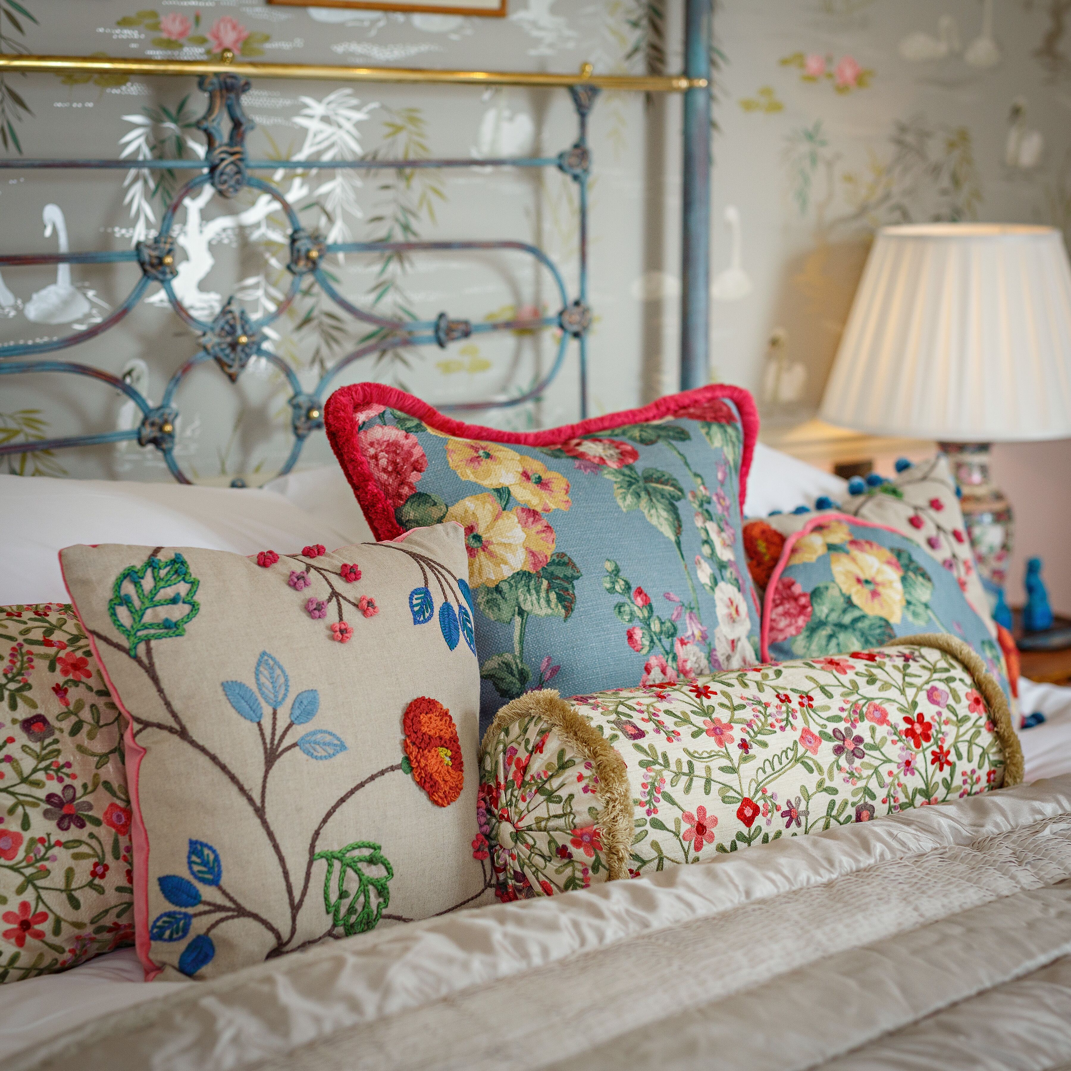 A bed with floral-patterned pillows and a metal-framed headboard.