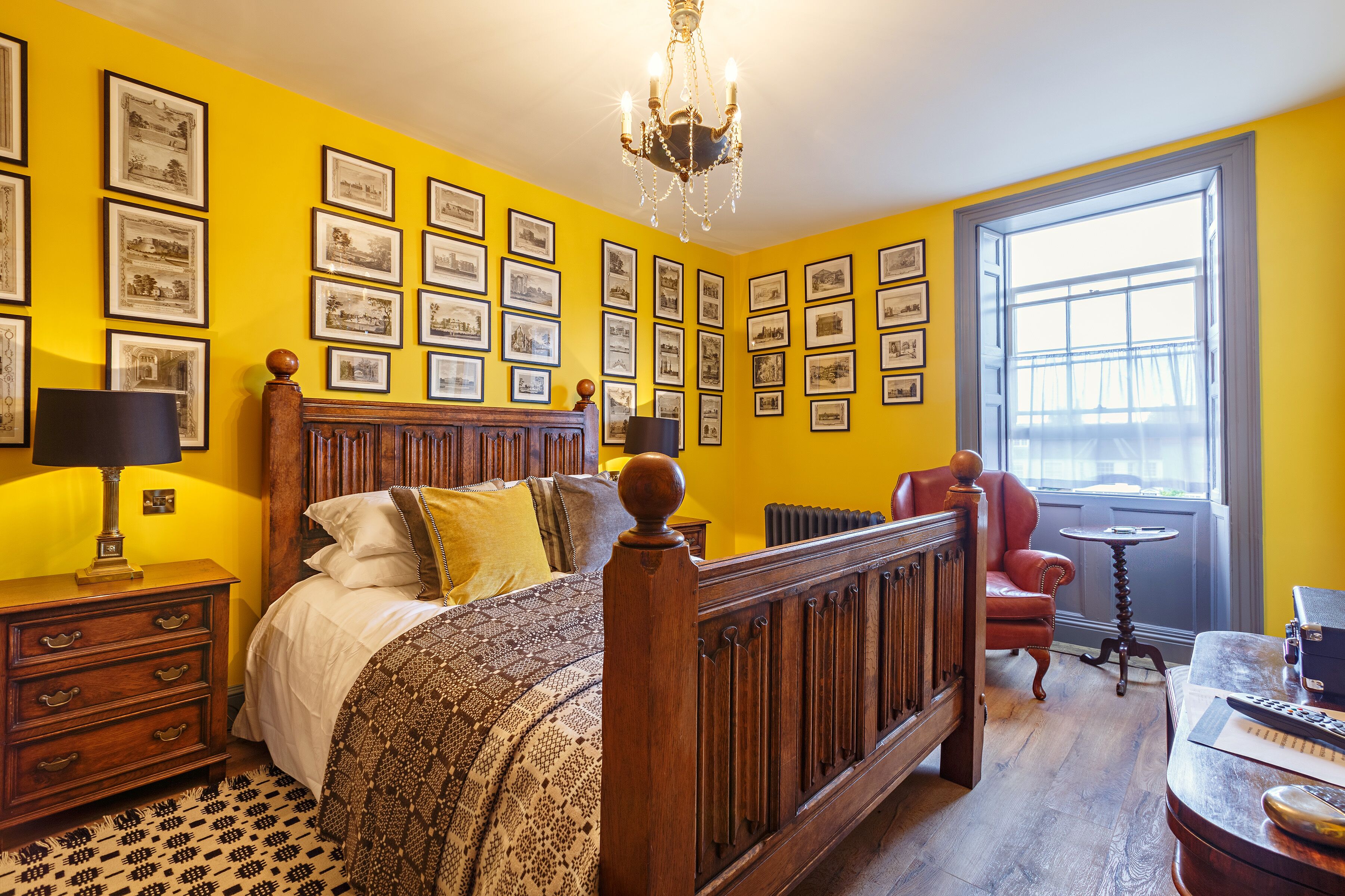 A room with a bed, a wooden dresser, a chair, a table, and a window with a view.