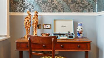 A wooden desk with a vintage radio, a framed picture, and a decorative vase.