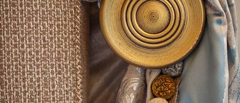 A close-up of a textured fabric with a circular wooden object and decorative pom-poms.