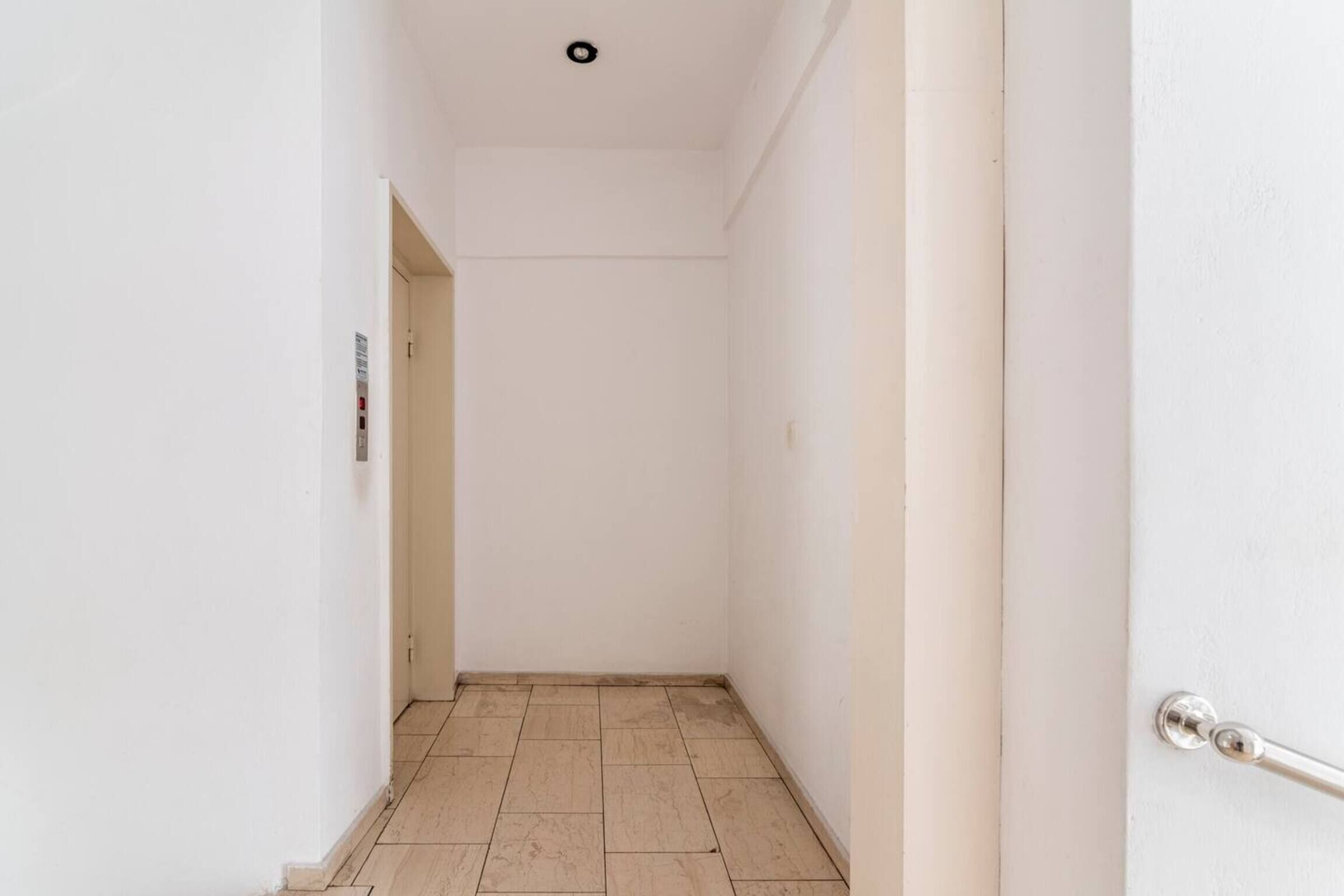 A narrow hallway with white walls and a tiled floor.
