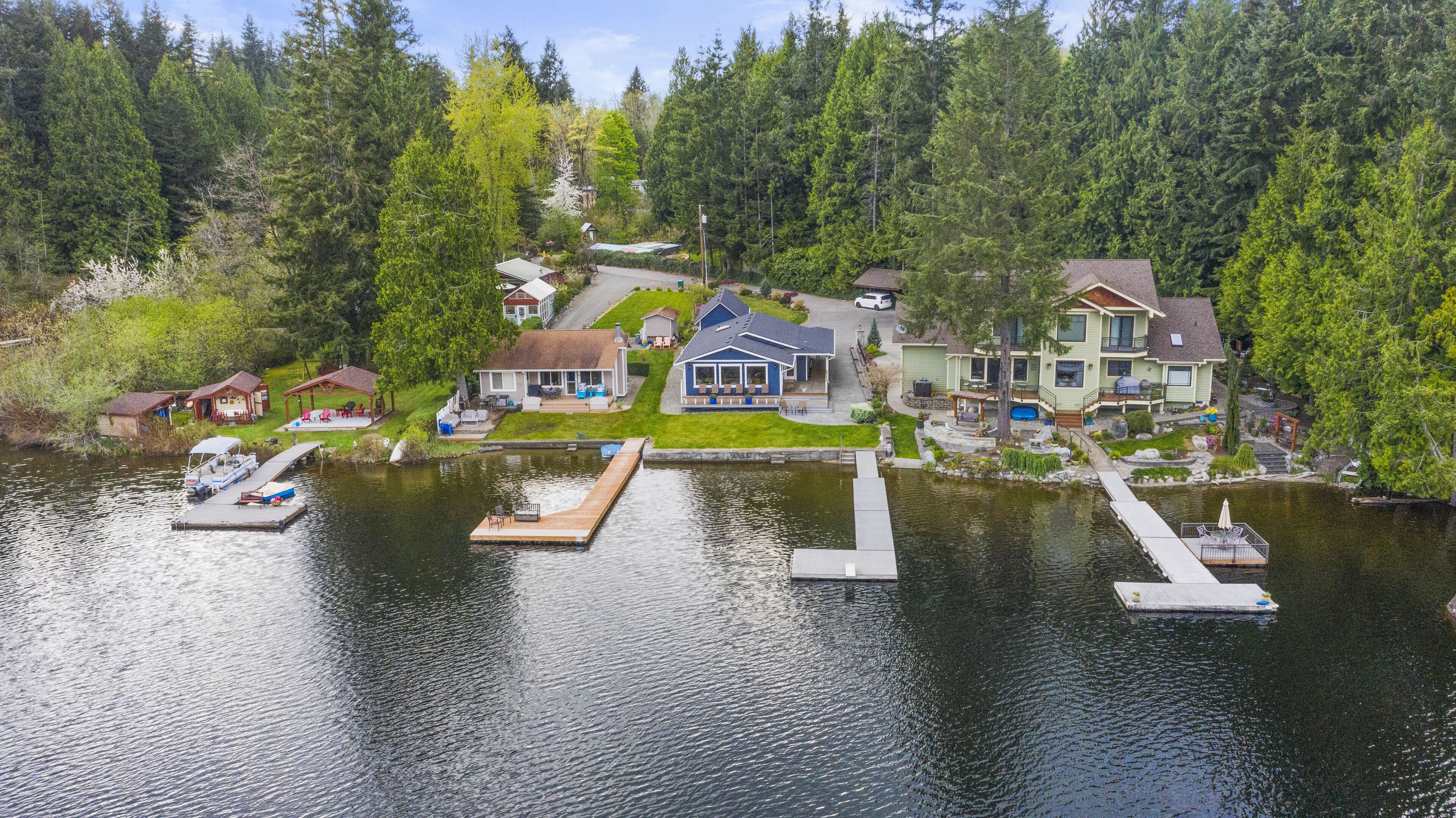 A lakeside property with multiple houses, a dock with boats, and a well-maintained garden.