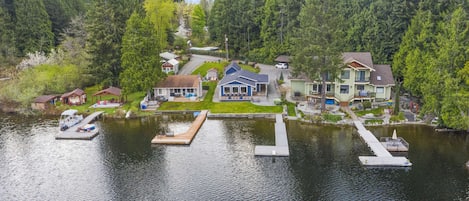 A lakeside property with multiple houses, a dock with boats, and a well-maintained garden.