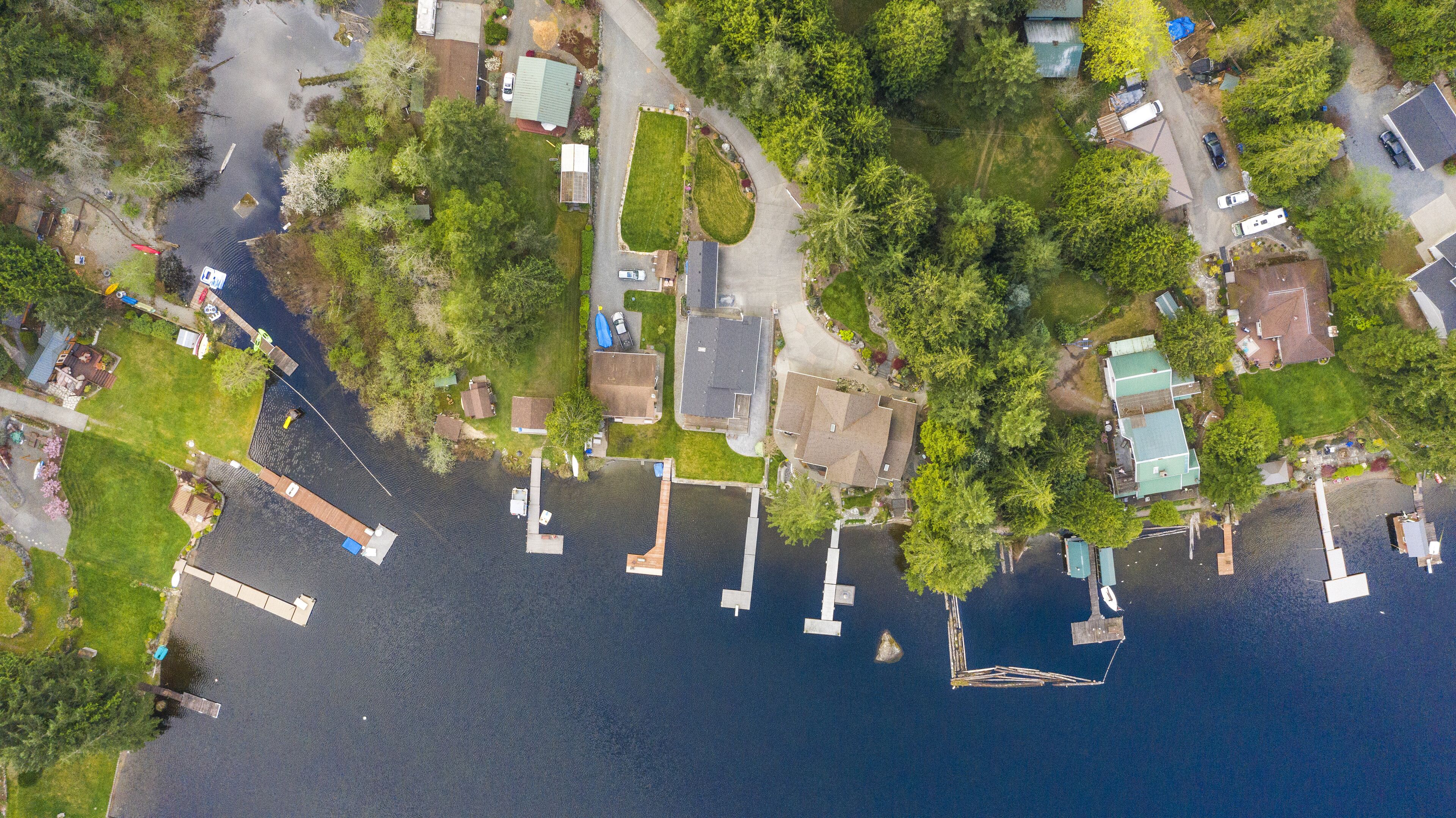 An aerial view of a residential area with houses, a dock, and a small boat.