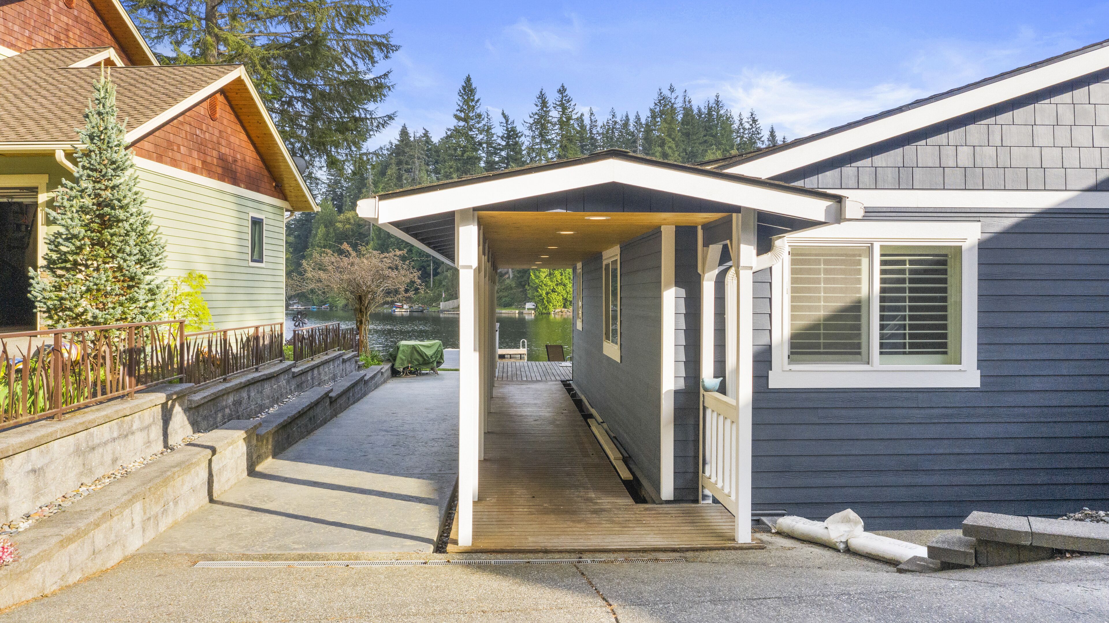 A covered porch leading to a house with a view of a lake and trees.