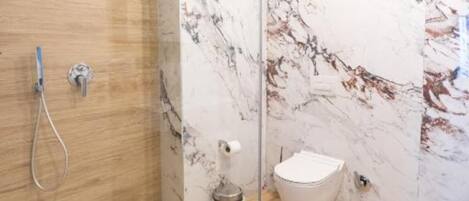 A modern bathroom with a marble wall, a wooden floor, and a white toilet.