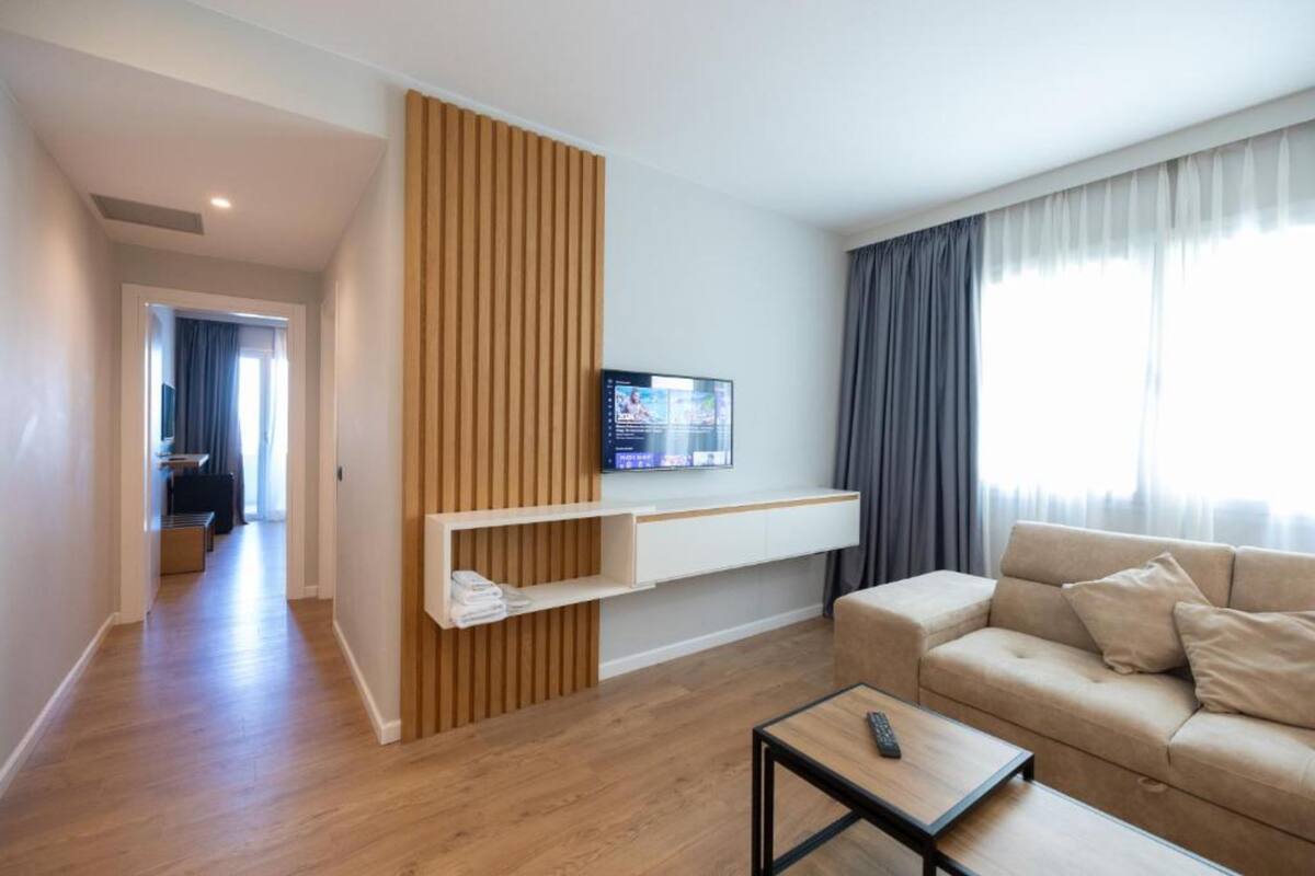 A modern living room with a sofa, a coffee table, and a TV mounted on a wall.