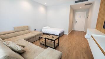 A modern living room with a sofa set, a small table, and a bed.