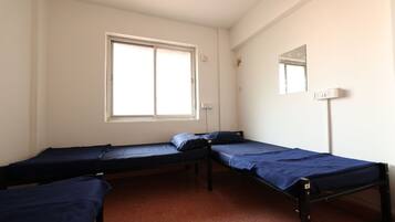 Habitación tipo dormitorio con dos camas individuales, una ventana, un espejo y una toma de corriente.