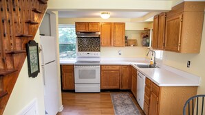 A kitchen with wooden cabinets, a white stove, and a sink. - Charming Dorset Cottage Retreat.  (Dorset)