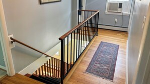 A staircase with wooden steps and black railings, a patterned rug on the floor, and a window with blinds. - Charming Dorset Cottage Retreat.  (Dorset)