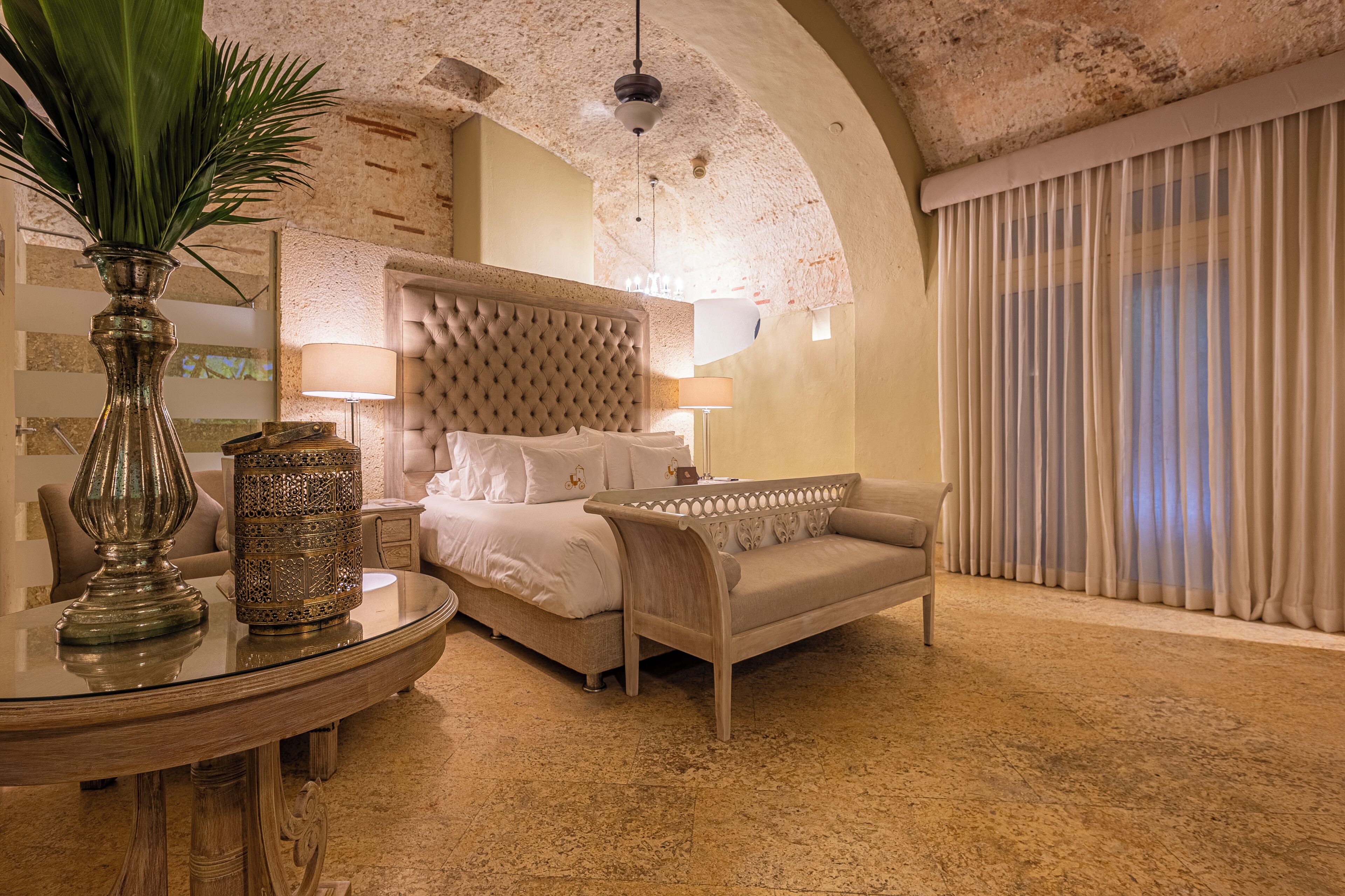 Habitación de hotel con cama, sofá, mesa redonda y lámpara.