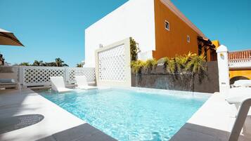 Een buitenzwembad, parasols bij het zwembad en ligstoelen