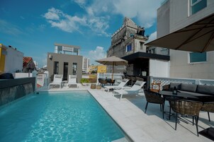 Una piscina al aire libre, sombrillas, sillones reclinables de piscina