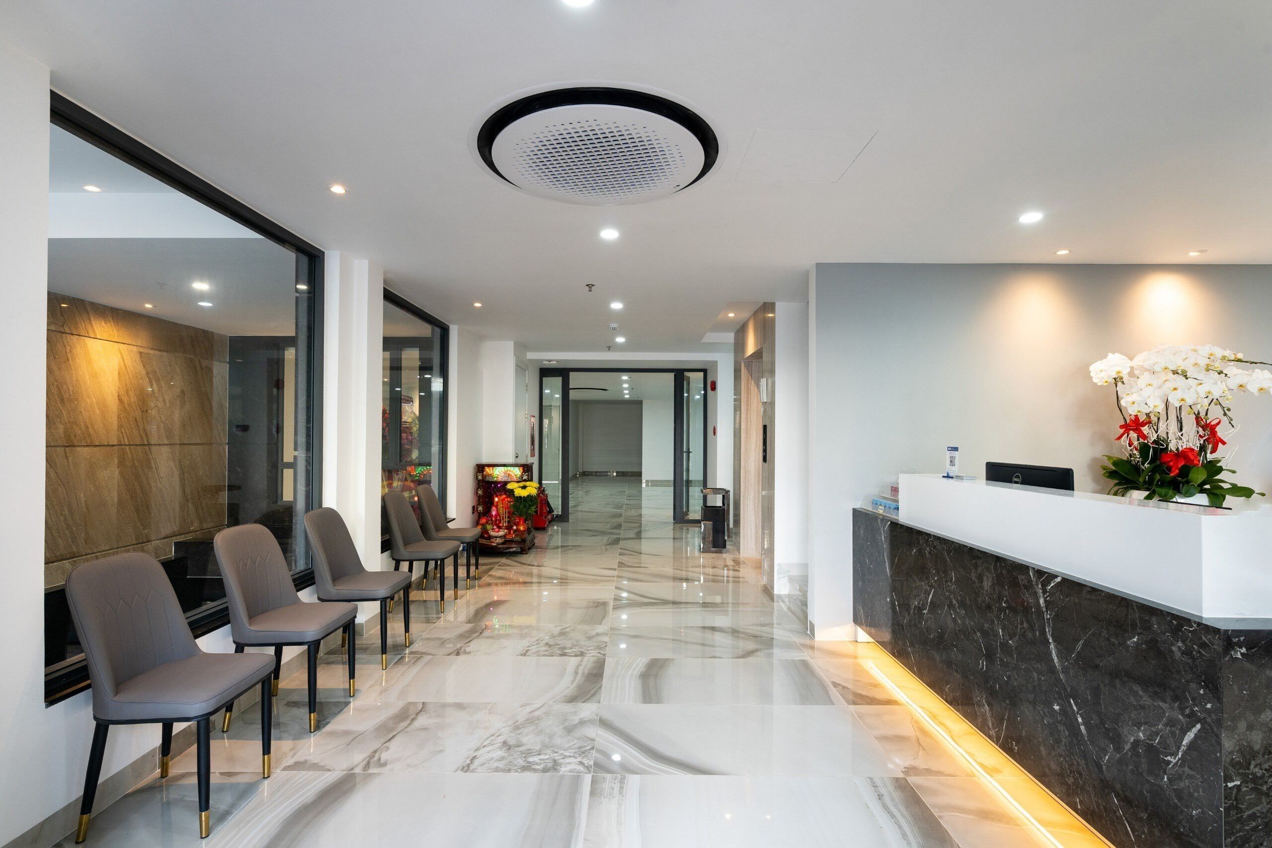Een moderne hotellobby met een marmeren vloer, een receptiebalie en een zithoek met stoelen.