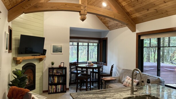 A cozy interior with a fireplace, bookshelves, a dining area, and a kitchen with a sink. - Cabin on the Boardman River (Traverse City)