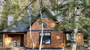 A wooden cabin with a stone foundation, a dark roof, and a small porch. - Cabin on the Boardman River (Traverse City)
