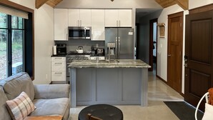 A modern kitchen with a central island, stainless steel appliances, and a wooden ceiling. - Cabin on the Boardman River (Traverse City)