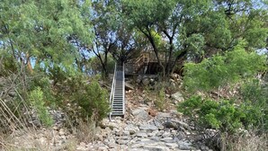 A rocky path leading to a wooden staircase surrounded by trees and vegetation. - Secluded & Spacious River Retreat With A View  (Roosevelt)