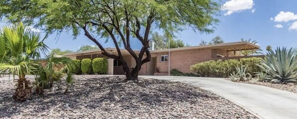 A building with a brick exterior, a tree in the foreground, and a clear sky. - Don’t pay full price if you only need one room. SEE NOTES pool, whole house (Tucson)