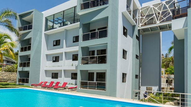 Um hotel moderno com piscina, várias varandas e vista para os arredores.