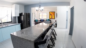 Cozinha moderna com bancada de granito, eletrodomésticos pretos e área de bancada com assentos.