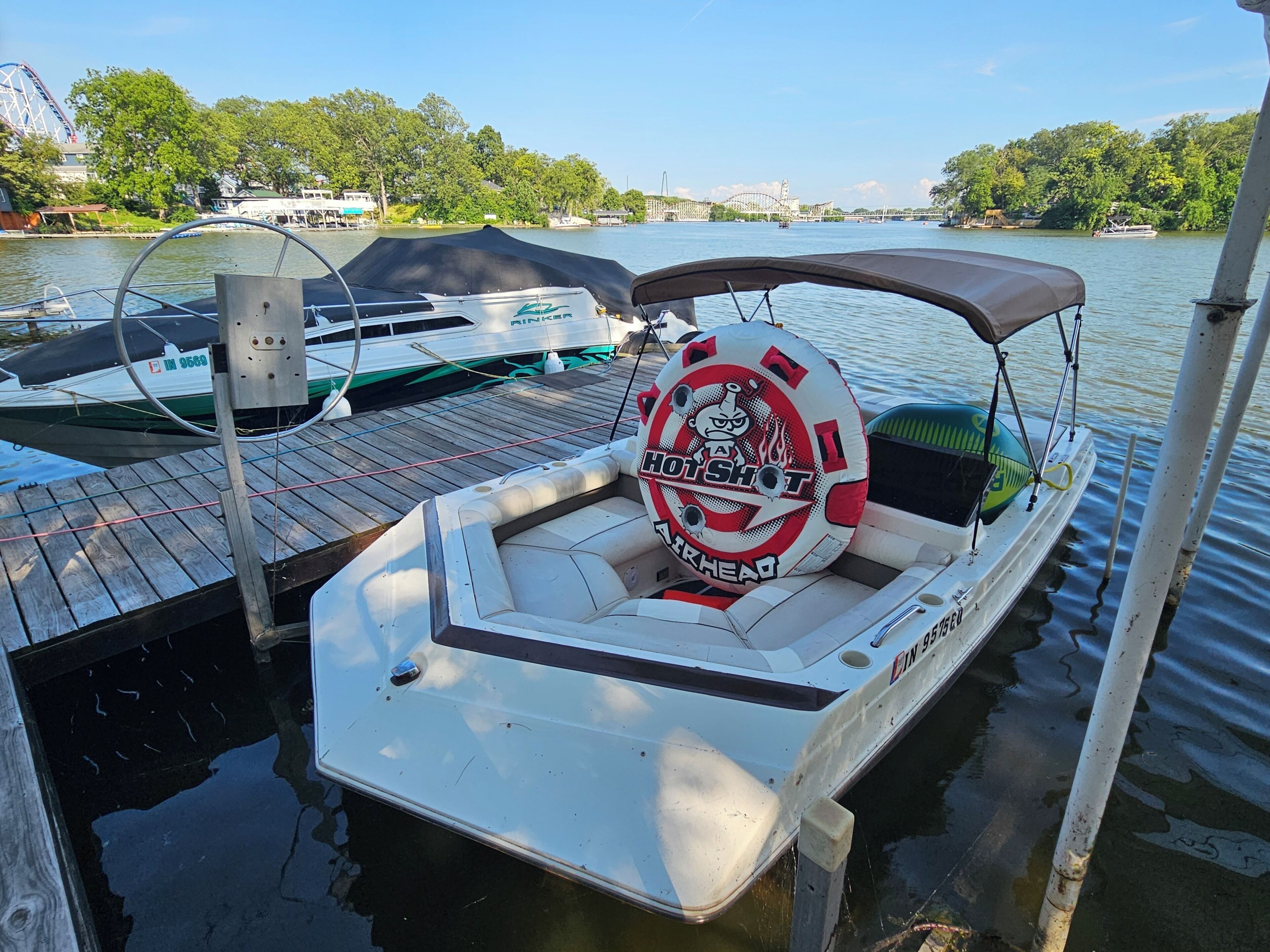 A boat docked at a pier with a life preserver and a logo that reads 'Hot Shot Airhead.'