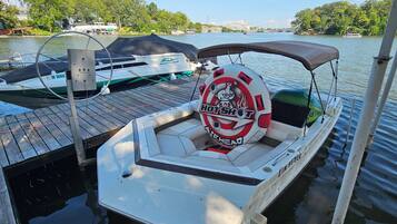 A boat docked at a pier with a life preserver and a logo that reads 'Hot Shot Airhead.'