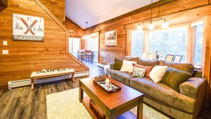 A cozy lodge interior with a wooden interior, a sofa, a coffee table, and a sign indicating it's a ski lodge.