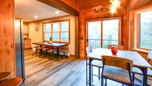 A wooden interior with a dining area, kitchen, and large windows.