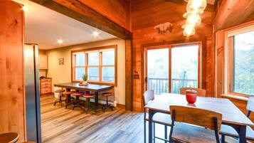 A wooden interior with a dining area, kitchen, and large windows.
