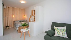 A modern bedroom with a bed, bedside table, and a green sofa. - Nice apartment in Labin with WiFi (Labin)