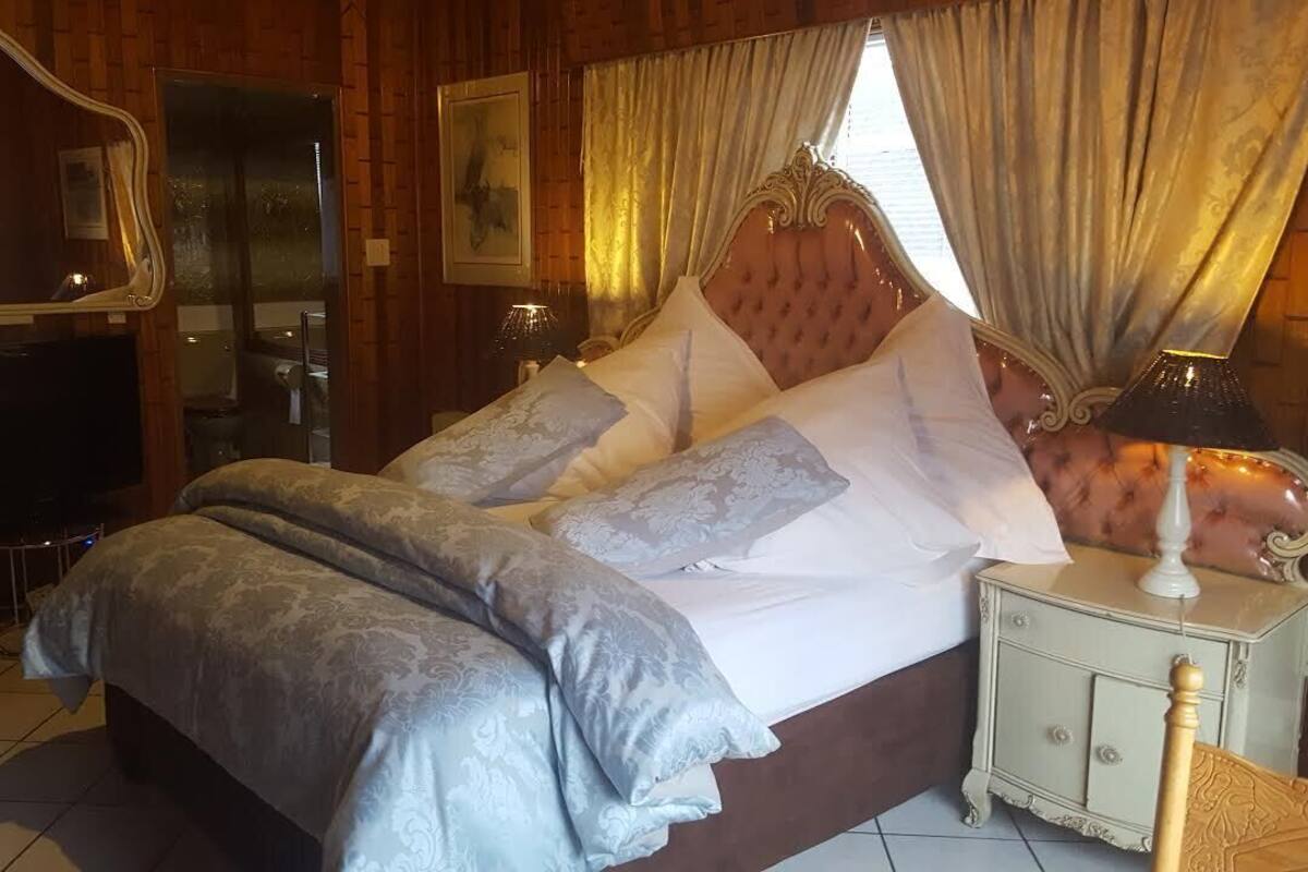 A bedroom with a large bed, a vanity with a mirror, and a television.
