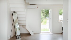 Un intérieur moderne avec un escalier, un grand miroir et une porte donnant sur un espace extérieur.
