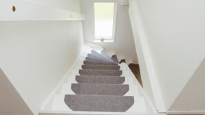 Un escalier étroit, surmonté d’une lucarne, qui mène à l’étage supérieur.