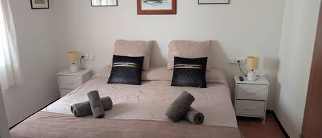 A neatly made bed with a patterned bedspread, two pillows, and two bedside lamps on nightstands.