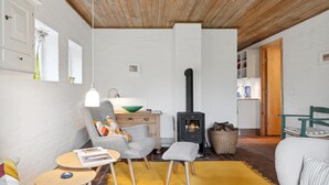 Un accogliente soggiorno con camino, soffitto in legno e zona pranzo con tavolo e sedie.