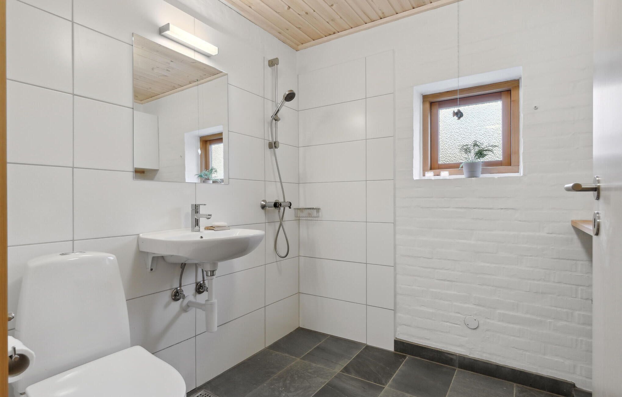 Une salle de bain avec un lavabo blanc, des toilettes et une douche.