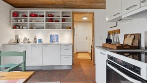 Una cucina con mobili bianchi, una macchina da caffè e un soffitto in legno.
