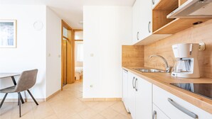 A modern kitchen with a Bosch coffee maker, a sink, and wooden cabinetry. - Beach front apartment in Kosljun with WiFi (Kosljun)