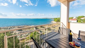 A balcony with a view of the sea, a table with a bottle and glasses, and a plate of food. - Beach front apartment in Kosljun with WiFi (Kosljun)