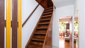 Una escalera de madera en un pasillo que conduce a un comedor con vistas a un jardín.