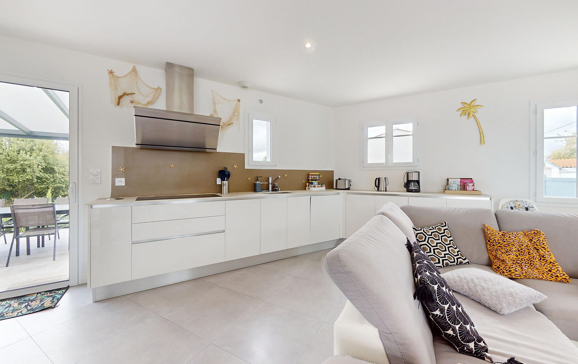 A modern kitchen with white cabinets, a stainless steel range hood, and a large window.